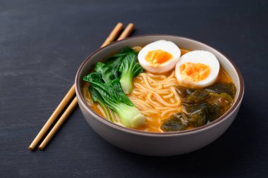 Yumurtalı baharatlı şehriye çorbası, yosun ve siyah arka planda bok çuvalı, Asya eriştesi tarzı.