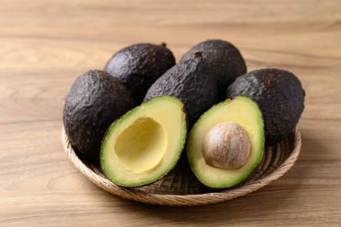 Olgun hass avokado meyvesi sepetin içinde ahşap arka planda