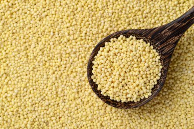 Organic yellow millet grain in spoon with millet grain background, Healthy food ingredient, Top view clipart