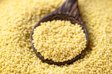 Kaşık içinde organik sarı darı taneleri, sağlıklı besin maddeleri