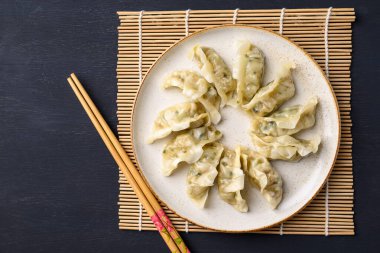 Domuz eti ve sebzeyle dolu buğulanmış hamur köftesi ve siyah arka planda çubuklar, Top view.