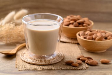 Bardaktaki badem sütü ahşap masada, alternatif süt bitkiden yapılır, süt içermez.