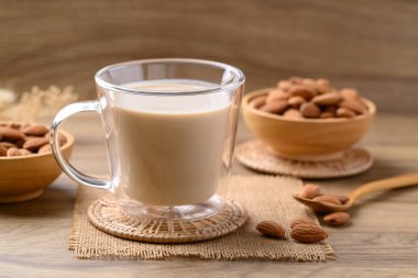 Bardaktaki badem sütü ahşap masada, alternatif süt bitkiden yapılır, süt içermez.