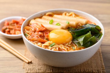 Spicy noodles soup with Tteokbokki, Wakame seaweed and fresh egg yok eating with kimchi cabbage clipart