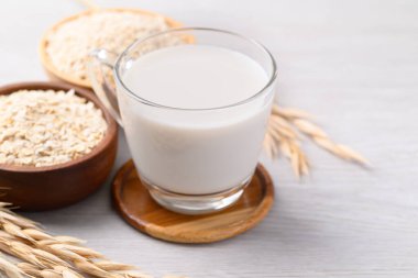 Beyaz arka planda yulaf ezmesi ve yulaf ezmesi bardakta yulaf sütü, süt içermeyen bitkiden yapılan alternatif süt.