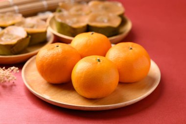 Mandarin portakallı meyve ve yapışkan pirinç keki (Nian Gao), kırmızı zemin üzerinde Çin Yeni Yıl keki