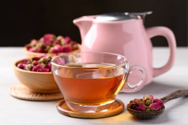 Kurumuş gül goncası, beyaz ve siyah arka planda çaydanlık, sağlıklı çiçek çayı.