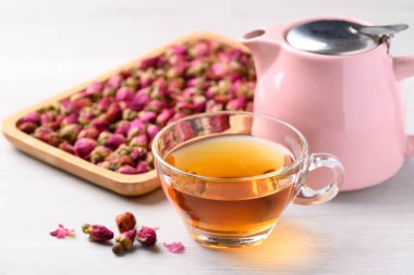 Kurumuş gül goncası ve beyaz arka planda çaydanlık, sağlıklı çiçek çayı.