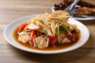 Tayland yemeği (Som Tum), baharatlı papaya salatası domuz sosisi ve ızgara tavuk kanadı. Yerel Tayland yemekleri.