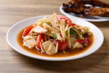 Tayland yemeği (Som Tum), baharatlı papaya salatası domuz sosisi ve ızgara tavuk kanadı. Yerel Tayland yemekleri.