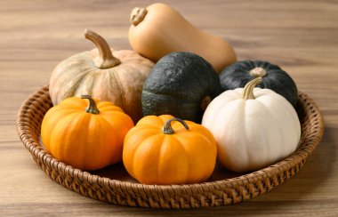 Tahta arka planda sepetin içinde çeşitli balkabakları