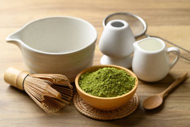 Kibrit yeşil çay tozu ile çay fincanı ve ahşap arka planda chasen.