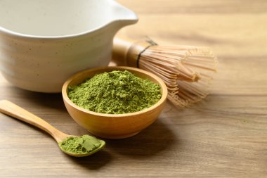 Kibrit yeşil çay tozu ile çay fincanı ve ahşap arka planda chasen.