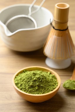 Kibrit yeşil çay tozu ile çay fincanı ve ahşap arka planda chasen.