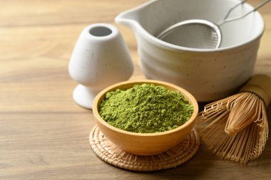 Kibrit yeşil çay tozu ile çay fincanı ve ahşap arka planda chasen.