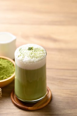 Ahşap zemin üzerinde köpük sütle kibrit yeşil çay.