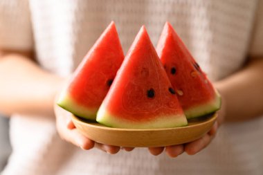 Elle tutulan tabakta dilimlenmiş karpuz, yaz mevsiminde tropik meyve.