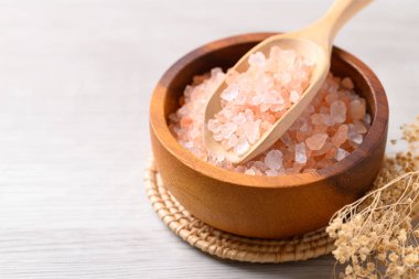 Himalaya 'nın organik pembe tuzu ahşap kasede beyaz masada kepçeyle, sağlıklı besin maddeleriyle.