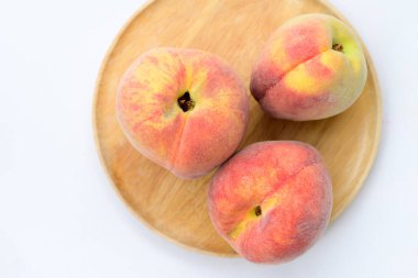 Şeftali meyvesi ahşap tabakta, beyaz arka plan, üst manzara