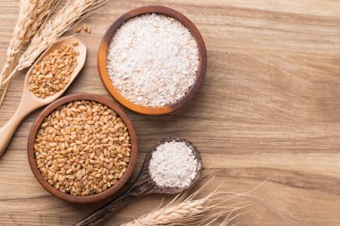 Tahta arka planda buğday taneli tam buğday unu, masa üstü manzaralı.