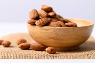 Tahta kasede beyaz arka planda çiğ badem tohumu.