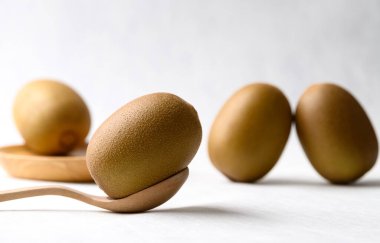 Tahta kaşıklı taze kivi meyvesi ve beyaz arka planda tabak, sağlıklı beslenme.