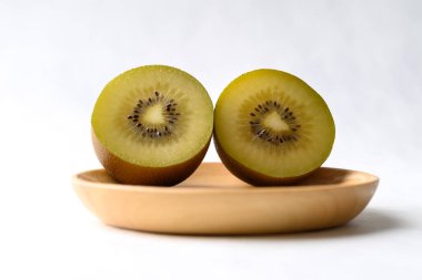 Taze batmış kivi meyvesi, beyaz arka planda ahşap tabak, sağlıklı meyve.