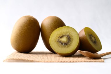 Çuval bezinde taze sungold kivi meyvesi beyaz arka planda ahşap kaşık sağlıklı beslenme
