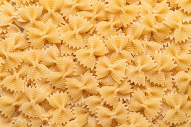 Kusursuz bir arka planda saçılmış çiğ farfalle makarna, papyon şeklindeki makarna, İtalyan yemek malzemeleri.