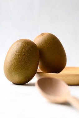 Beyaz arka planda tahta kaşıkla taze kivi meyvesi, sağlıklı beslenme.