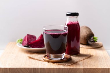 Taze pancar suyu bardakta ve şişe tahtada, sağlıklı bir içecek.