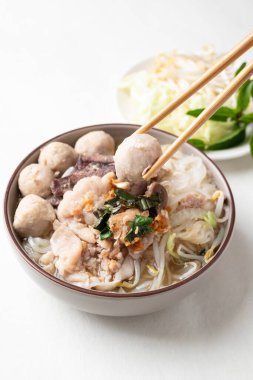 Tayland eriştesi çorbası dilimlenmiş domuz eti, kıyma, köfte ve ciğer beyaz arka planda taze sebzelerle yenir, geleneksel Tayland sokak yemekleri.