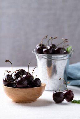 Tahta kasede taze kiraz, beyaz masada kova sağlıklı beslenme ve mevsimsel beslenme.