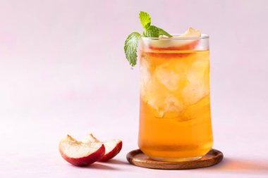 Buzlu şeftali çayı, taze şeftali dilimi ve pembe arka planda nane yaprağı, yaz içeceği.