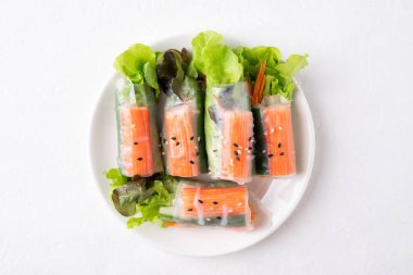 Yengeç sopasıyla salata rulosu, havuç, salatalık ve salatalıkla sarılmış pirinç kağıdı beyaz arka planda, Top view