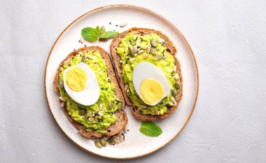Haşlanmış yumurtalı avokado tostu, ay çekirdeği, kabak çekirdeği ve tabakta susam tohumu, sağlıklı beslenme.
