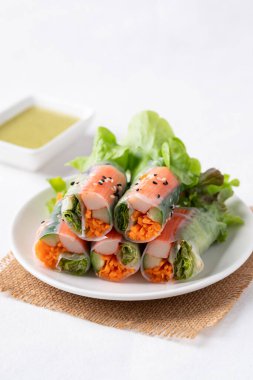 Yengeç sopasıyla salata rulosu, havuç, salatalık ve salataya sarılmış pirinç kağıdı ve sos.