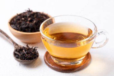 Beyaz arka planda kurutulmuş çay yaprakları, sağlıklı bitkisel sıcak içecek.