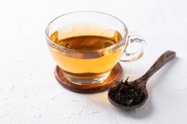 Bardakta siyah çay, beyaz arka planda kurutulmuş çay yaprakları, sağlıklı bitkisel sıcak içecek.