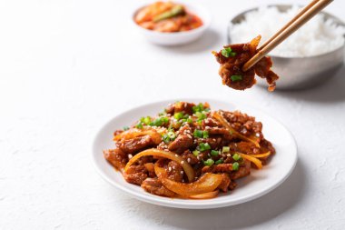 Beyaz arka planda pişmiş pirinç ve kimchi ile Kore usulü kızarmış baharatlı domuz eti (Bulgogi).