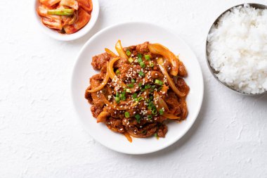 Beyaz arka planda pişmiş pirinç ve kimchi ile Kore usulü kızarmış baharatlı domuz eti (Bulgogi).