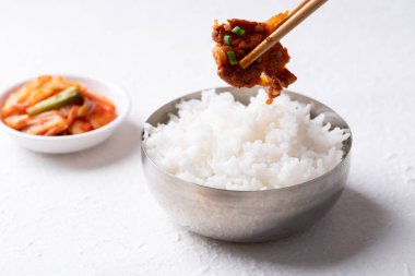 Beyaz arka planda pişmiş pirinç ve kimchi ile Kore usulü kızarmış baharatlı domuz eti (Bulgogi).