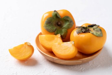 Tahta tabakta taze olgun hurma, beyaz arka plan, sonbahar tatlı meyvesi