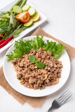 Yerel Tayland yemekleri, baharatlı domuz salatası (Larb Moo) beyaz arka planda taze sebzelerle yemek