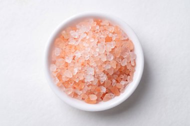 Himalaya pembe tuzu beyaz arka planda, sağlıklı besin maddeleri kasesinde.