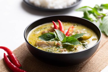 Tayland yeşil köri tavuğu, siyah kâse içinde pirinç ve malzemelerle.