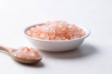Himalaya pembe tuzu kasede ve kaşıkla beyaz arka planda, sağlıklı besin maddeleri