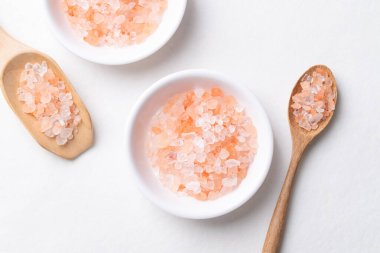 Himalaya pembe tuzu beyaz arka planda kaşık, sağlıklı besin maddeleri ile birlikte kasede üst görünüm