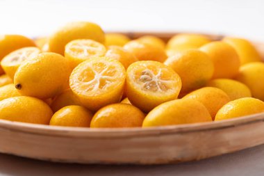 Beyaz arka planda bambu sepetinde taze kumkatlar.