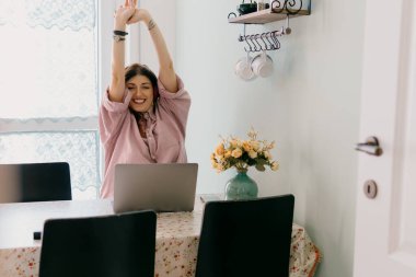 Happy young woman relaxes while working from home on laptop